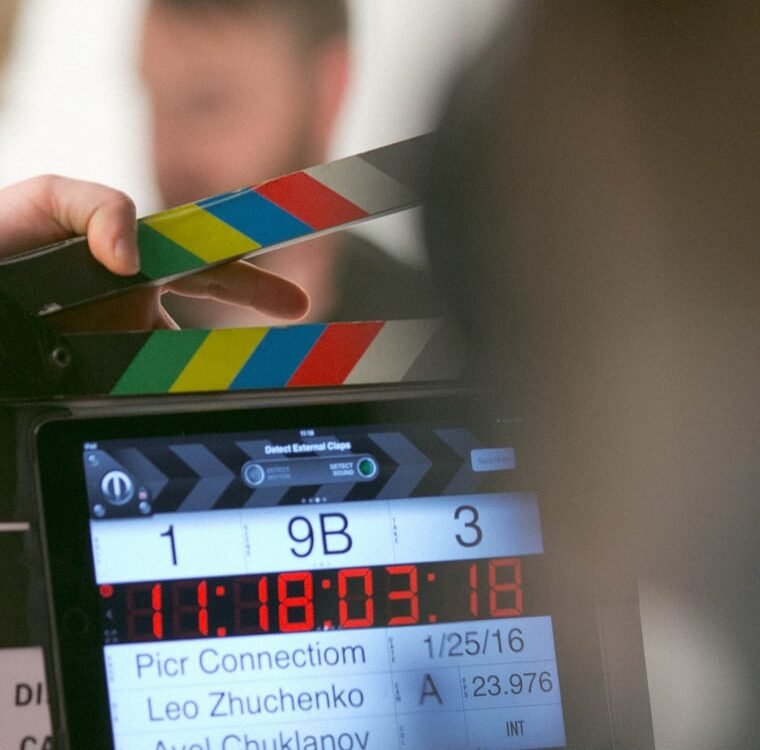 A clapperboard held in front of a camera monitor on set.