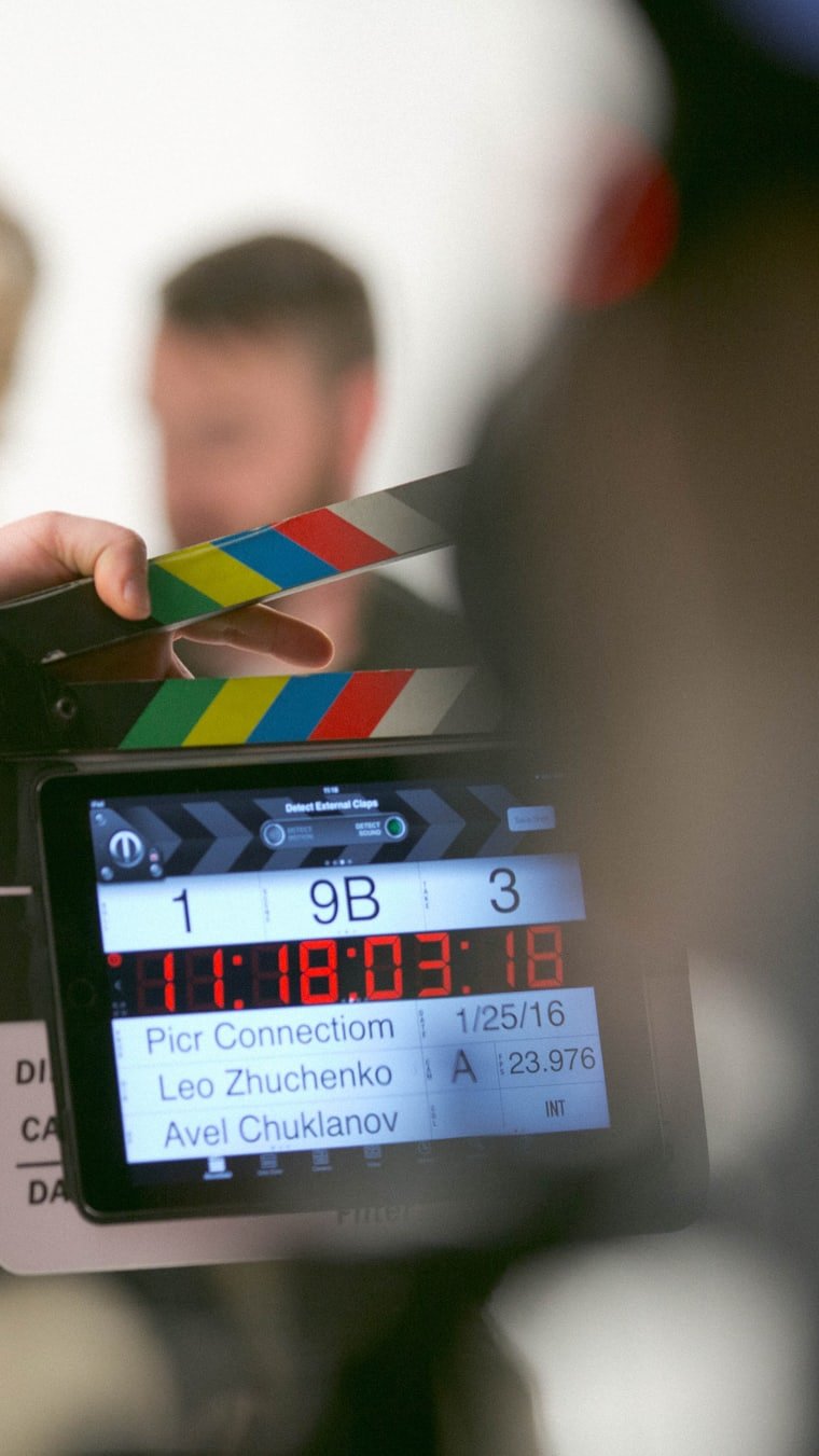 A clapperboard held in front of a camera monitor on set.