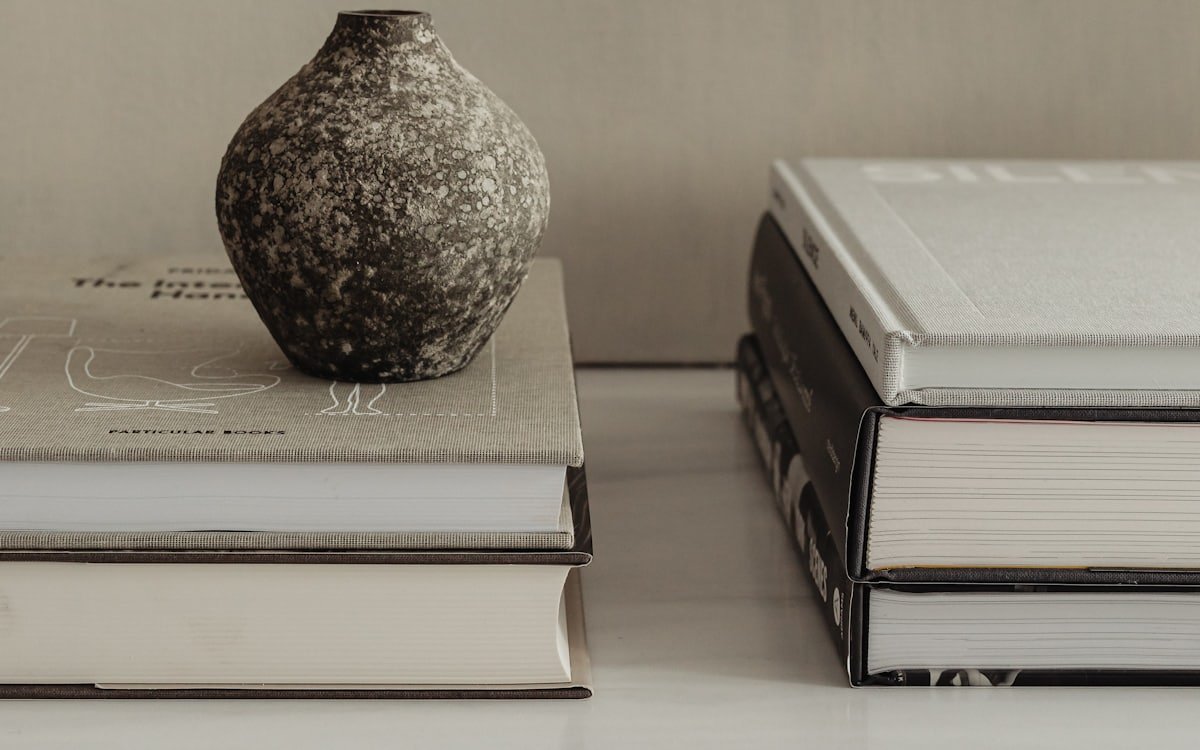 A textured ceramic vase resting on a stack of hardback books.