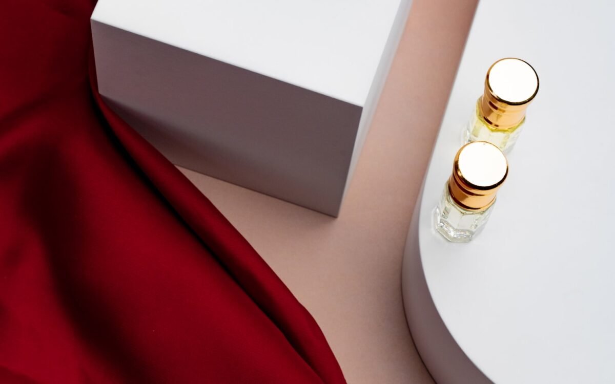 Glass bottles styled on white plinths with draped red silk.