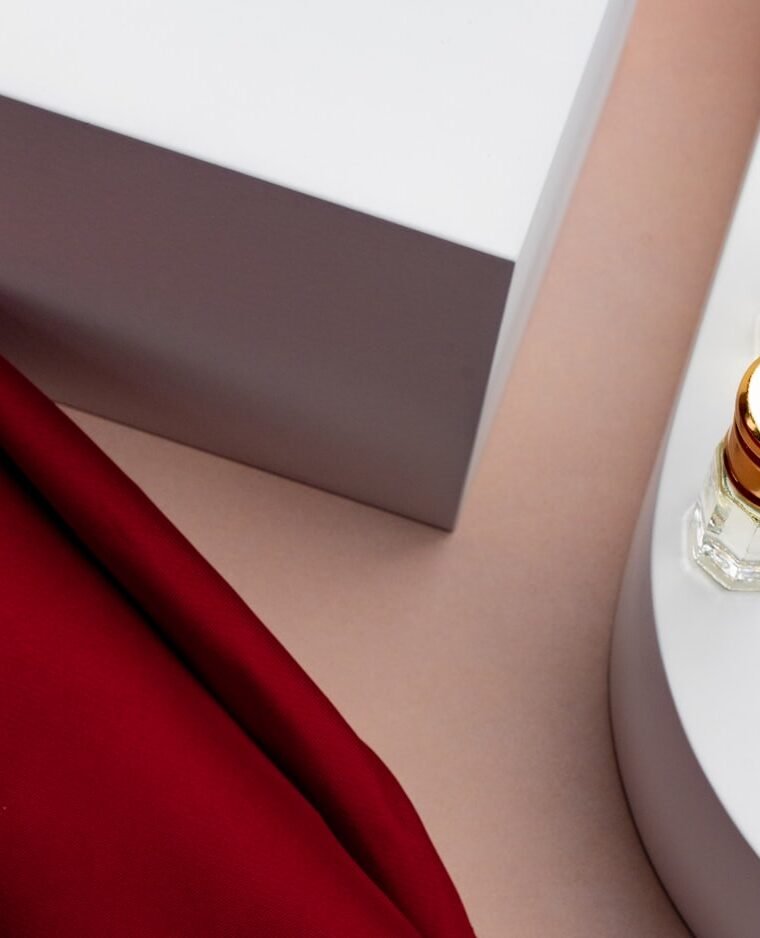 Glass bottles styled on white plinths with draped red silk.