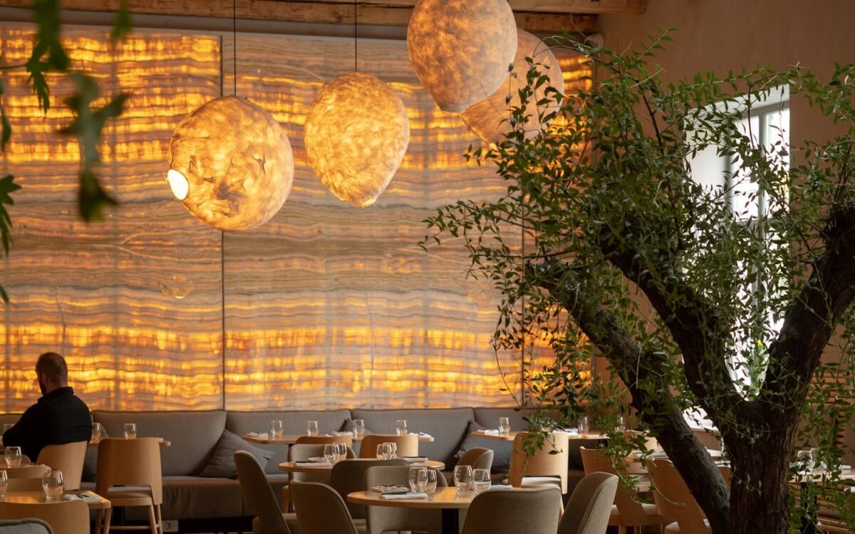 A warm restaurant interior with backlit stone walls and globe pendant lights.